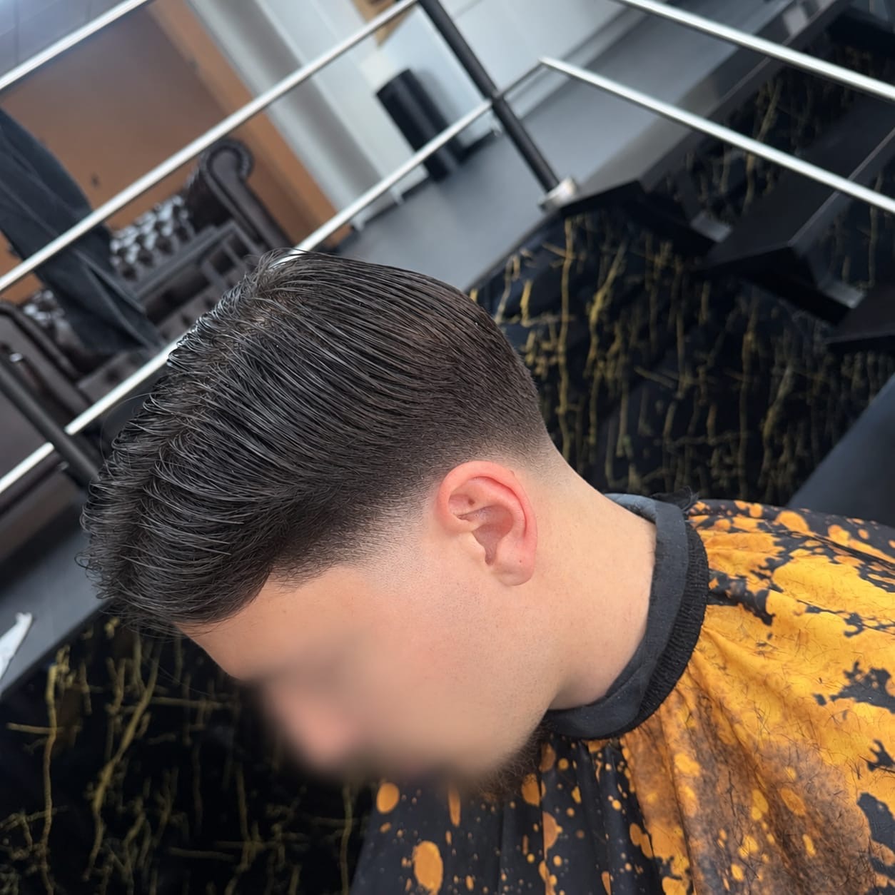 Achterovergekamd haar met een skin fade, voor de zwarte marmeren wand met gouden aders