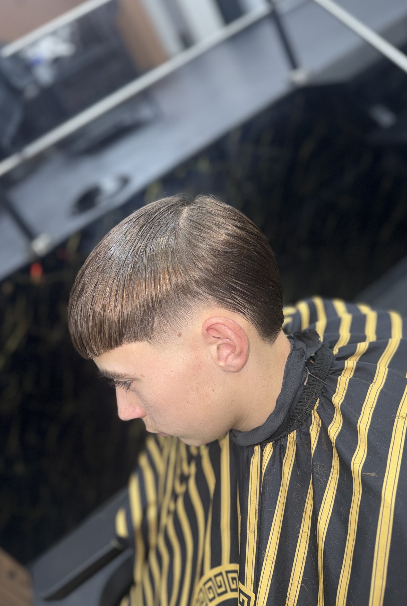 Strak geknipte pony met een taper, van bovenaf gezien, gestreepte kapmantel
